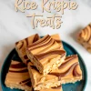 Stacked peanut butter Rice Krispie treats with chocolate swirls on a dark teal plate, displayed on a marble surface. The text overlay reads “Peanut Butter Rice Krispie Treats” in playful script.