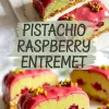 Pistachio raspberry entremet with a glossy pink raspberry glaze, vibrant green pistachio mousse, and a layer of whole raspberries inside, presented on a crunchy biscuit base and garnished with chopped pistachios.