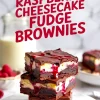 Stack of three layered raspberry cheesecake fudge brownies on white round board, with visible gooey raspberry sauce and chocolate topping, styled with blurred background.