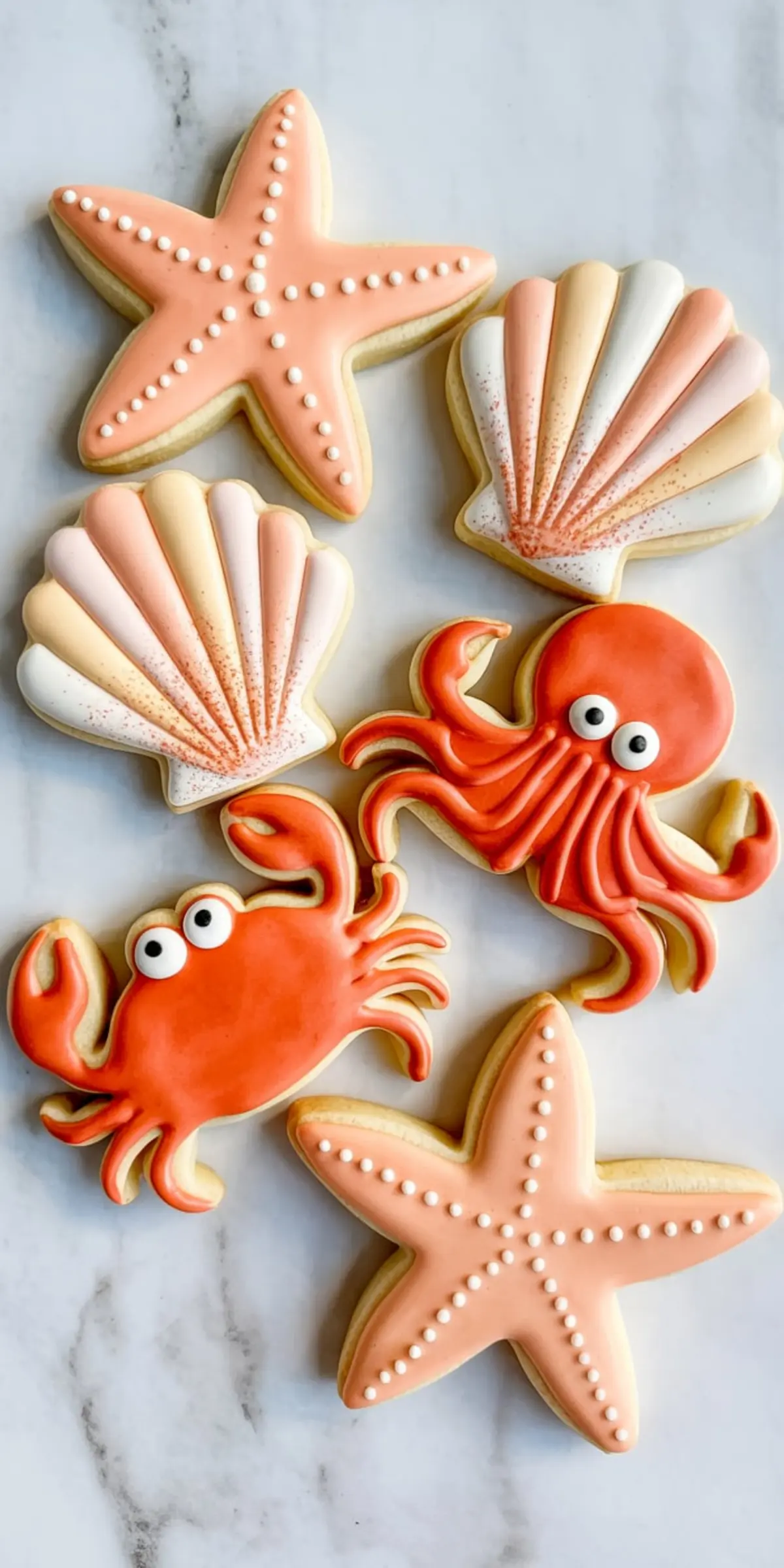 Beach-themed sugar cookies featuring orange crabs, coral octopus, pastel seashells, and starfish, all decorated with smooth royal icing.