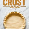 Overhead image of a crimped unbaked pie crust in a foil pan on a floured surface, with the text “Pie Crust Recipe” in bold above the crust.