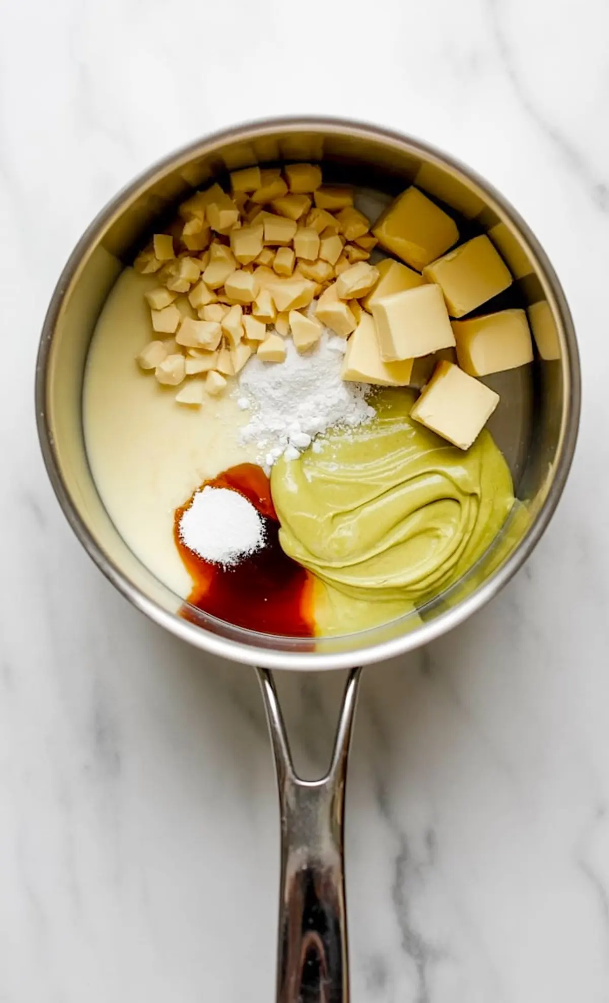 Saucepan with brigadeiro ingredients including white chocolate, pistachio paste, butter, vanilla extract, and cornstarch arranged for cooking.