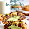 Close-up of gooey pistachio cream-stuffed chocolate chip cookies, broken in half to reveal vibrant green pistachio filling and rich melted chocolate chunks.