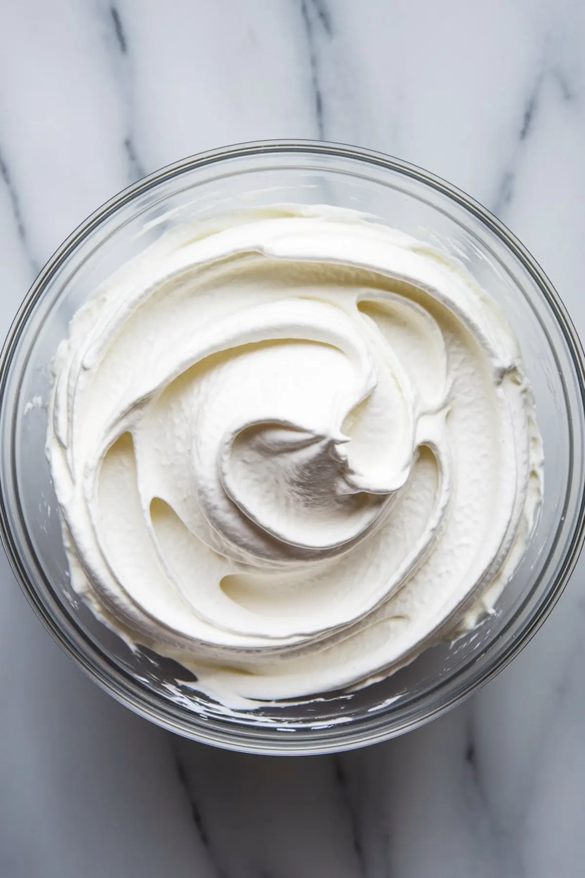Smooth, freshly whipped cream in a glass bowl with soft peaks. This whipped topping is used for decorating pistachio pudding desserts, adding a creamy finish to pistachio pudding cake, pistachio birthday cake, and pistachio pudding pie.