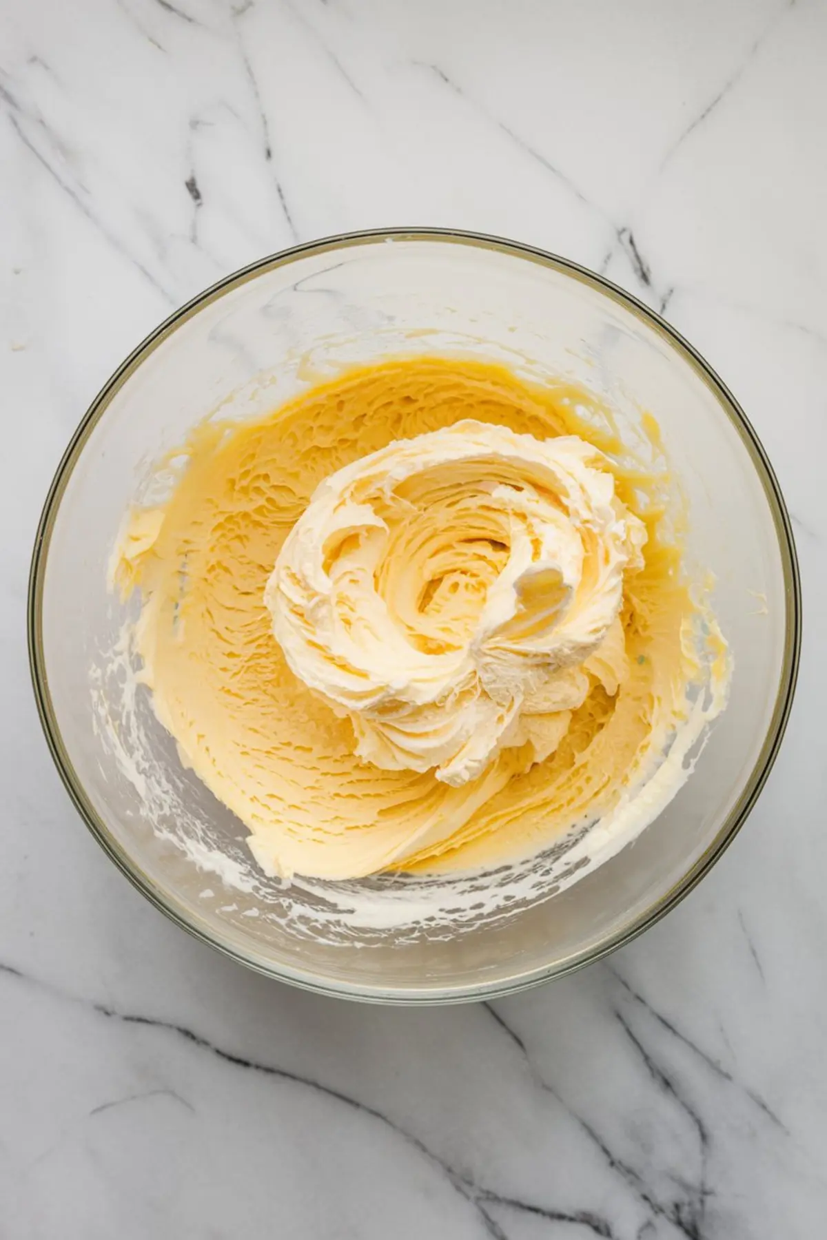 Creamed butter and sugar mixture whipped until fluffy in a glass bowl for the base of pistachio ricotta cookie dough.