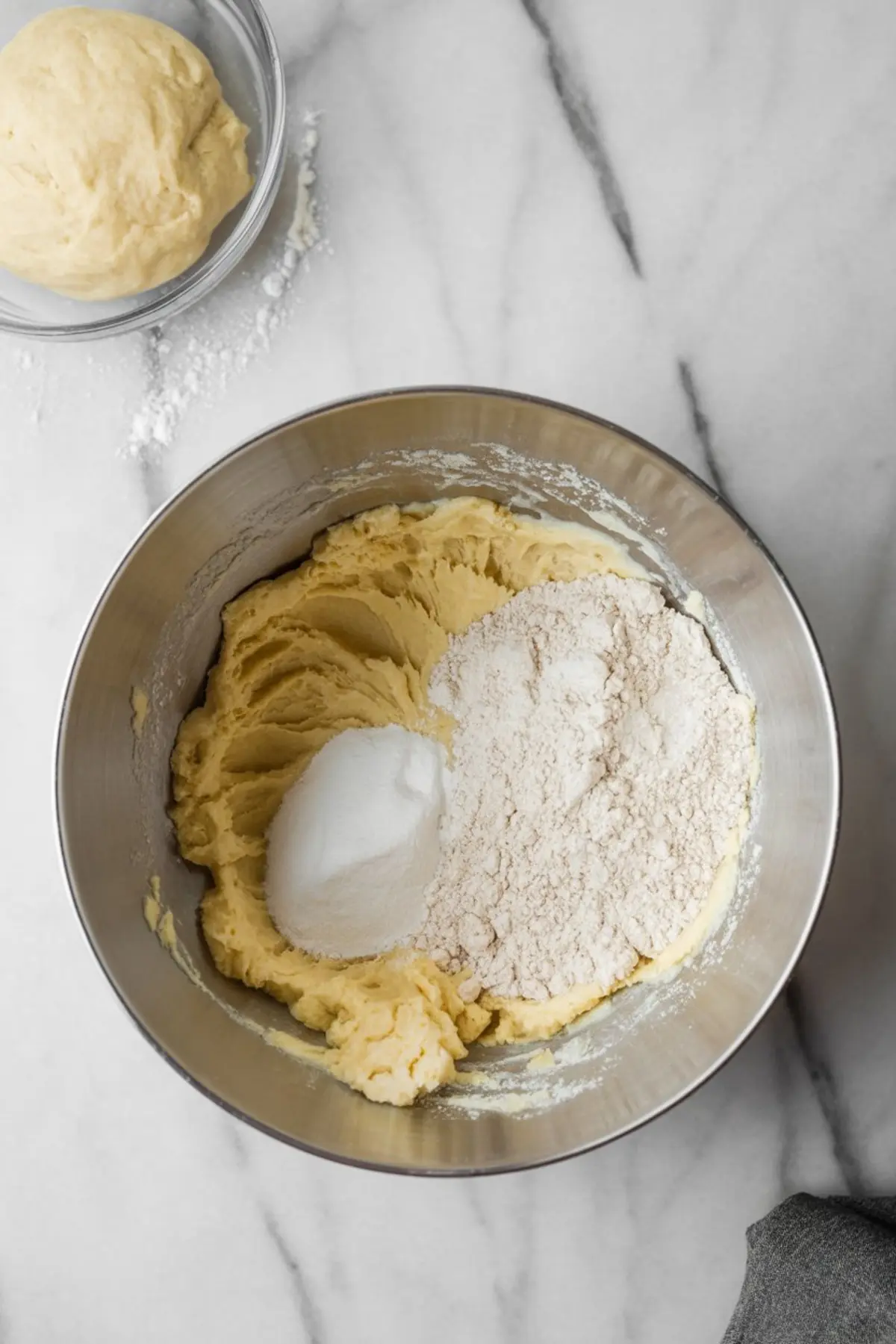 Mixing bowl with creamed butter and sugar partially combined with flour and baking powder, in the process of preparing dough for pie crust or crumble topping.