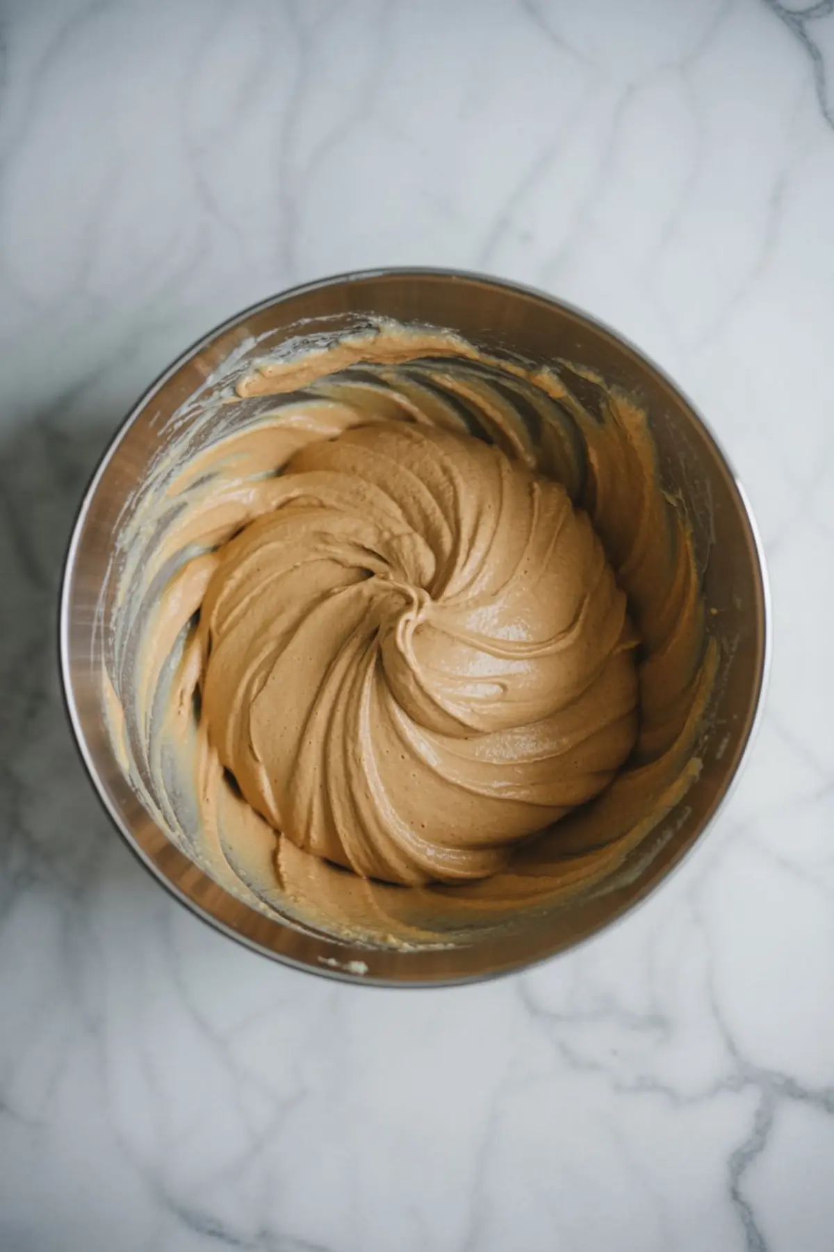 Creamy whipped peanut butter mixture in a metal mixing bowl with swirled texture, ready for layering in a no-bake dessert.