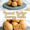 Stack of oat-filled peanut butter energy balls on a slate serving board with a cut-open ball showing a dense nutty texture, topped with the recipe title in bold.