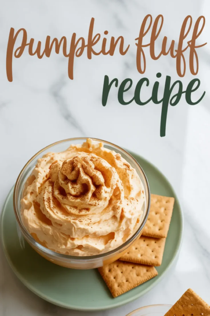Overhead view of whipped pumpkin fluff served in a glass dish with a cinnamon sprinkle, styled with square graham crackers on a green plate and “pumpkin fluff recipe” text above on a marble background.