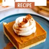 Close-up of a pumpkin pie bar slice with a swirl of whipped cream and cinnamon on a blue plate, emphasizing the creamy pumpkin layer and golden crust.