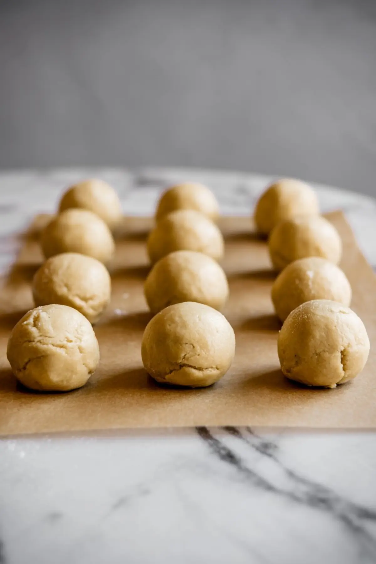 Raw cookie dough balls placed evenly on parchment paper, prepped for baking.