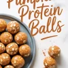 Flat lay Pinterest image with pumpkin protein balls topped with oats on a blue plate and two balls in the foreground, one bitten to reveal a soft center, with “Pumpkin Protein Balls” written in bold script across a white marble background.