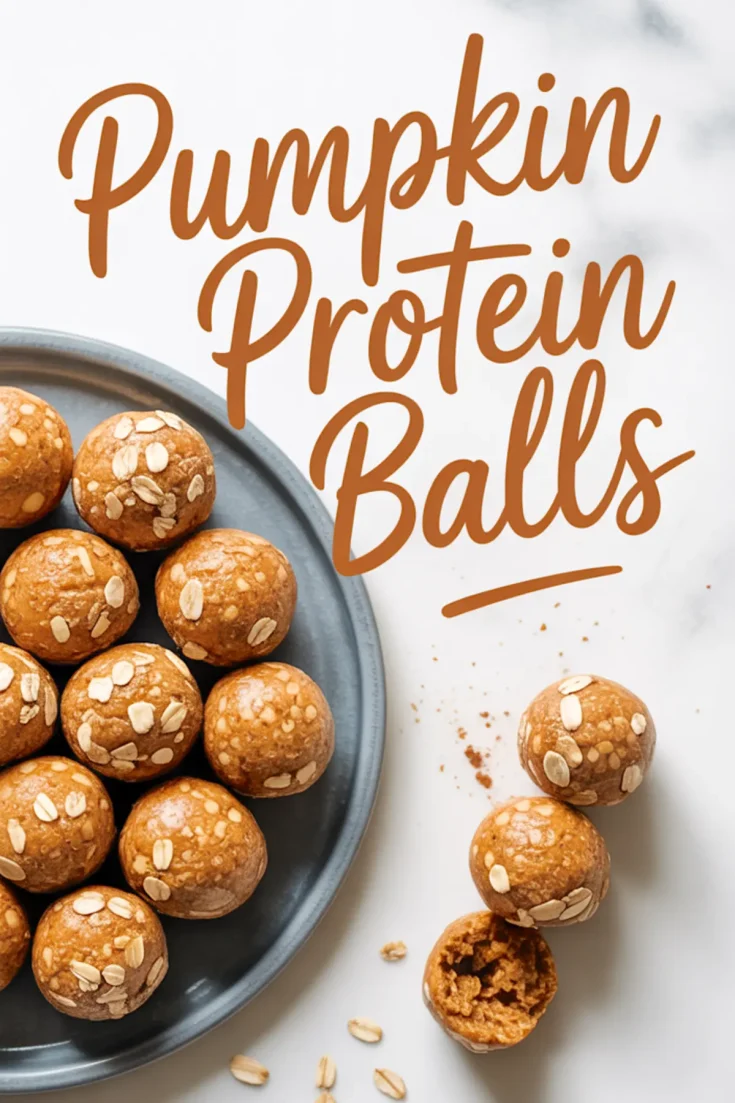 Flat lay Pinterest image with pumpkin protein balls topped with oats on a blue plate and two balls in the foreground, one bitten to reveal a soft center, with “Pumpkin Protein Balls” written in bold script across a white marble background.