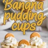 Banana pudding cups layered with creamy pudding, banana slices, and cookie crumbs, topped with whipped cream and a vanilla wafer, arranged on a white serving tray.