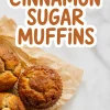 Freshly baked cinnamon sugar muffins with golden brown tops on parchment paper, with bold stylized text that reads “Cinnamon Sugar Muffins” above them.