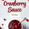Overhead shot of a bowl of homemade cranberry sauce with a spoon, surrounded by text that reads “Best Cranberry Sauce Recipe,” with scattered cranberries on a marble background.