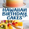 Hawaiian birthday cake with pastel ombré frosting in orange and yellow, topped with kiwi, mango, cherries, and tropical flowers, with a slice cut to display layers of fruit-filled sponge cake.