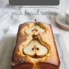 Golden pear cake loaf topped with halved pears, baked into a soft, moist crumb, displayed on a marble slab with bold “Pear Bread” and “pear bread recipes” text overlay.