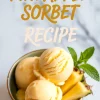 Bowl of pineapple sorbet topped with mint leaves and pineapple slices with text overlay that reads “Pineapple Sorbet Recipe.”