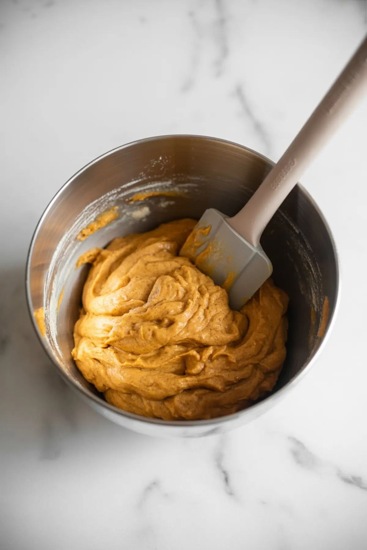 Pumpkin snickerdoodles with crackled cinnamon tops arranged on parchment paper, paired with a stack of soft, chewy cookies in warm orange tones.