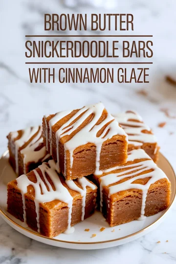Plate of thick, square snickerdoodle bars made with brown butter and topped with cinnamon glaze, stacked against a white marble background with recipe title text.