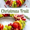 Holiday fruit wreath with a vibrant mix of sliced strawberries, kiwi, orange, grapes, apples, and halved pomegranates arranged on a round platter with rosemary, perfect for Christmas fruit tray ideas, Santa fruit tray, and Thanksgiving fruit centerpieces.