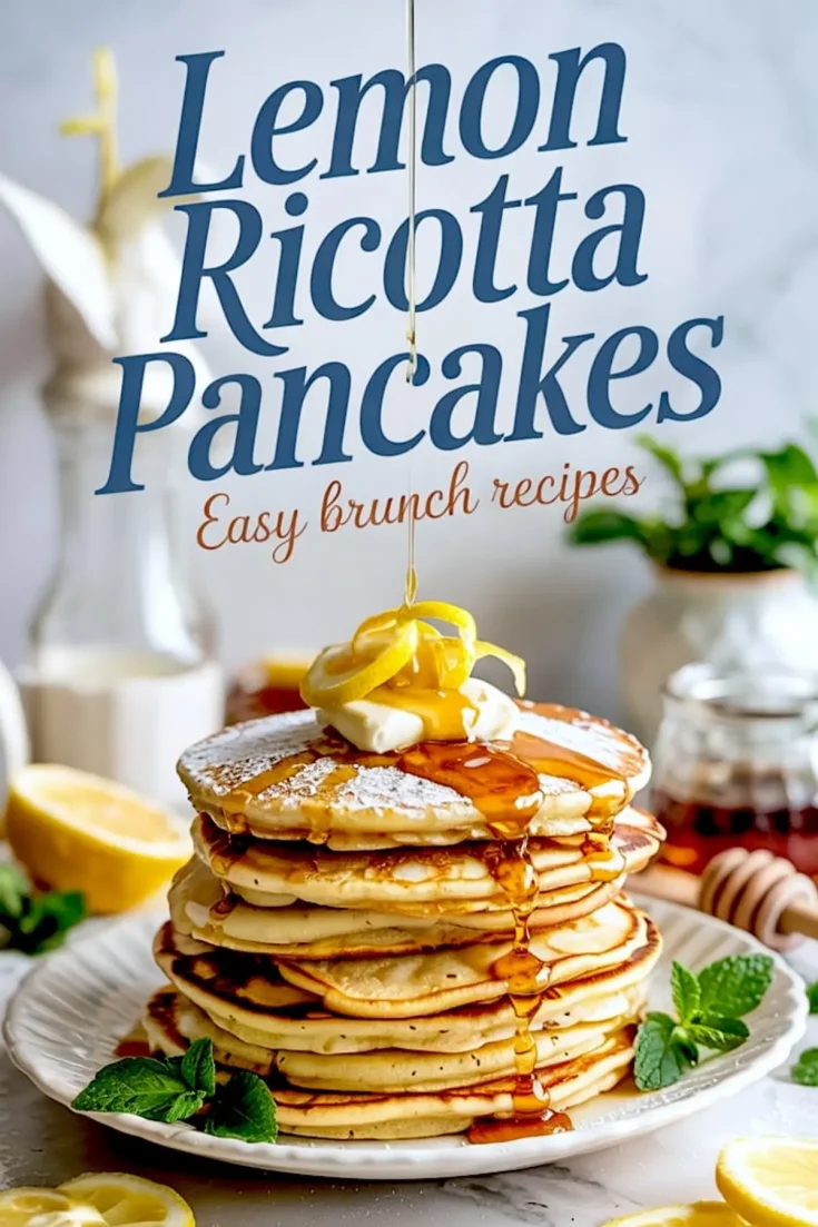 Stack of lemon ricotta pancakes drizzled with syrup and topped with butter and lemon zest, with a honey dipper and sliced lemons in the background on a marble surface.