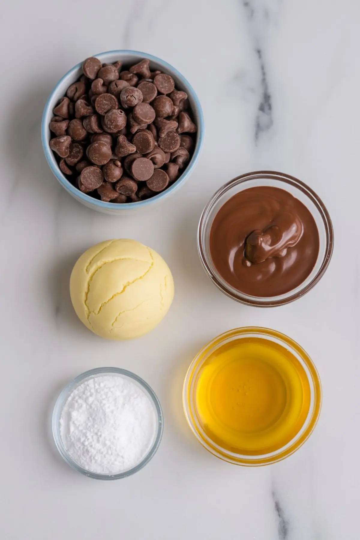 Flat lay of Thanksgiving cookie ingredients including chocolate chips, melted chocolate, yellow fondant, powdered sugar, and corn syrup in small glass bowls.