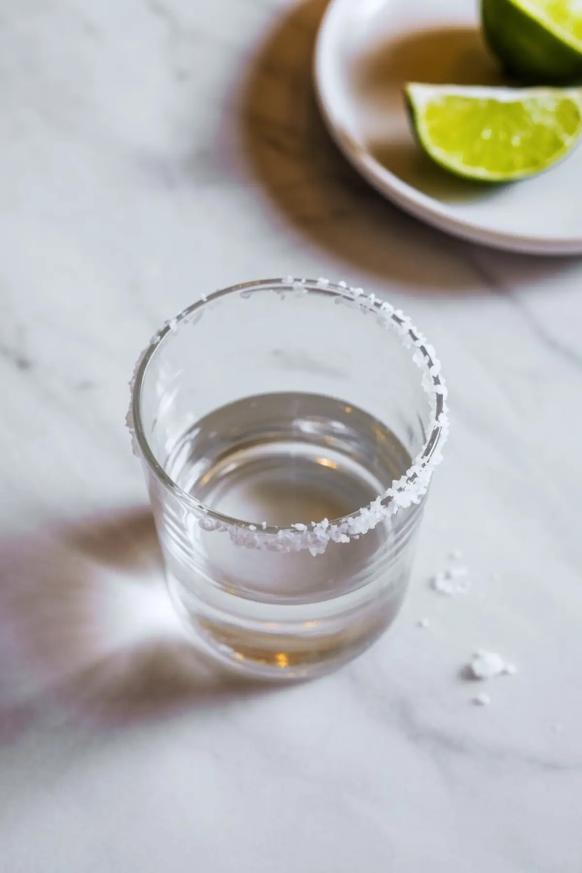 Whole pomegranate, a halved pomegranate, and two glass bowls filled with pomegranate seeds displayed on a round marble tray with a wooden spoon.
