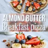 Pinterest-style collage of sliced almond butter breakfast pizza, decorated with banana coins, halved strawberries, blueberries, and granola, with bold central text reading “ALMOND BUTTER Breakfast pizza” above a close-up of a single slice.