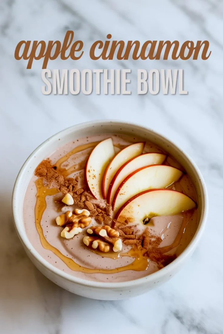 Apple cinnamon smoothie bowl topped with fresh apple slices, ground cinnamon, chopped walnuts, and maple syrup drizzle in a white bowl.