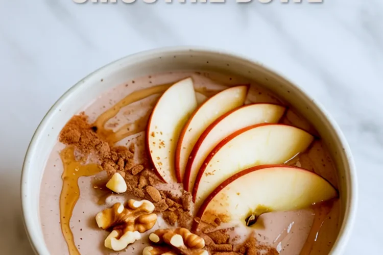 Apple cinnamon smoothie bowl topped with fresh apple slices, ground cinnamon, chopped walnuts, and maple syrup drizzle in a white bowl.
