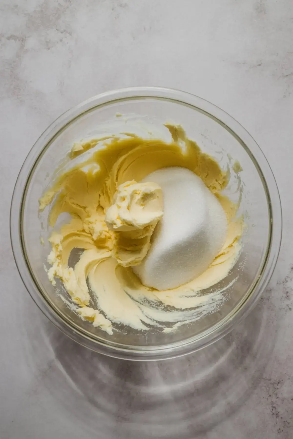 Butter and granulated sugar creamed together in a glass mixing bowl, an essential step in preparing cake batter or cookie dough for sweet dessert recipes and home baking.
