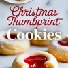 Plate of jam-filled thumbprint cookies dusted with powdered sugar, with text overlay in festive red script reading “Christmas Thumbprint Cookies – Perct Holiday Treats.”