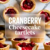 Cranberry cheesecake tartlets with golden crusts and glossy cranberry topping displayed on a marble surface, with bold text overlay reading “Cranberry Cheesecake Tartlets.”