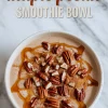 Maple pecan smoothie bowl topped with whole pecans, maple syrup drizzle, and a dusting of cinnamon, set against a light marble background with text overlay.