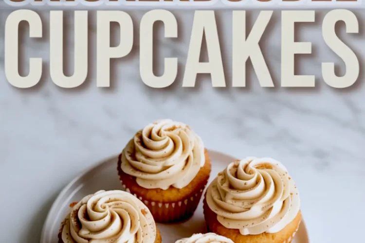 Four frosted snickerdoodle cupcakes with cinnamon-dusted buttercream on a round white plate, styled on a marble countertop.