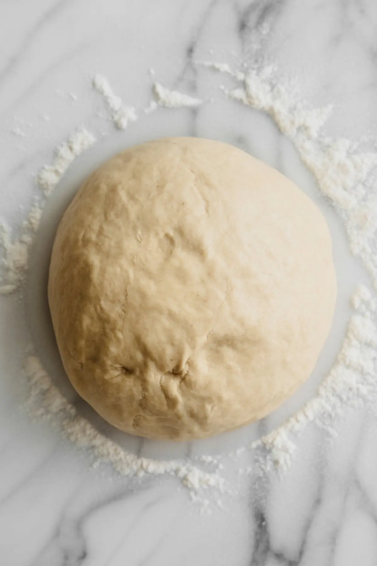Ball of raw tart dough on a lightly floured marble surface, ready to be rolled out.
