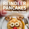Christmas-themed reindeer pancakes arranged with pretzels, banana slices, chocolate chips, and a strawberry on a round stack, drizzled with maple syrup on a white plate. Bold text overlay reads “Reindeer Pancakes - Christmas Morning Breakfast.”