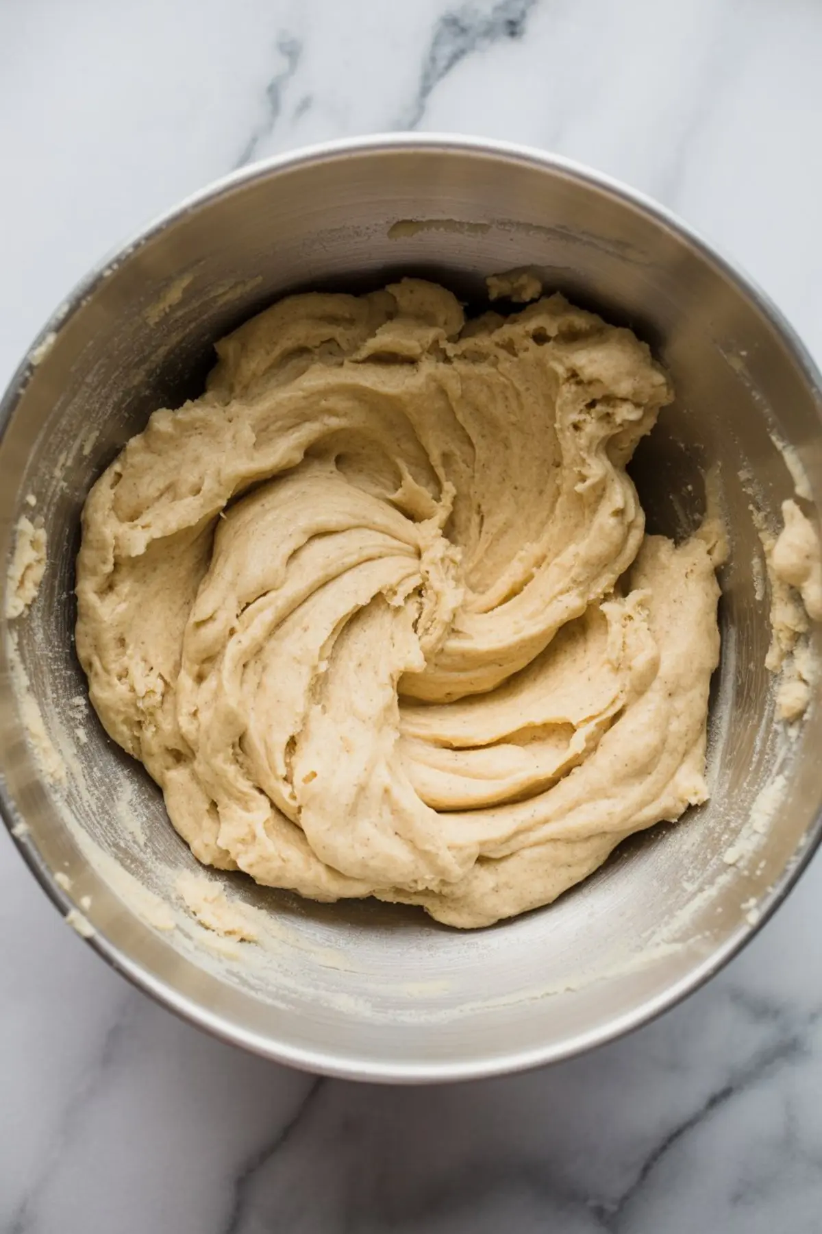 Vanilla cookie dough fully mixed in a metal bowl, showing a smooth and thick consistency ready for shaping and baking.
