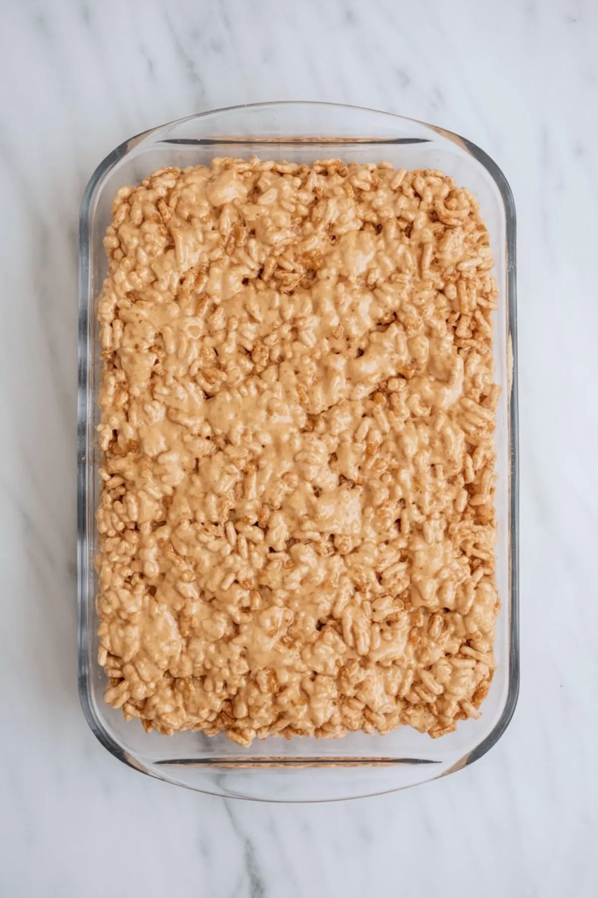 Melted butter and brown sugar heating together in a stainless steel saucepan, forming a glossy golden mixture viewed from above.
