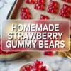 Freshly made strawberry gummy bears arranged in rows on a baking sheet lined with parchment paper. A small ceramic dish in the foreground holds a pile of red gummy bears, placed on a marble countertop with strong daylight illumination.