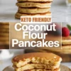A tall stack of coconut flour pancakes topped with blueberries and raspberries sits on a marble surface, paired with a bold text overlay reading keto friendly coconut flour pancakes, with a lower image showing fluffy sliced pancakes on a speckled plate.