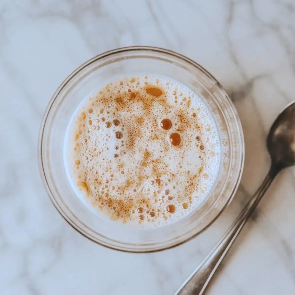 Activated yeast mixture sits in a glass bowl with foamy milk and sugar bubbles, prepared for Italian bomboloni dough.