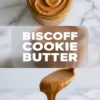 Angled close-up of a jar filled with smooth Biscoff cookie butter, showing thick creamy texture, soft swirl pattern, and warm caramel brown color on a neutral background.