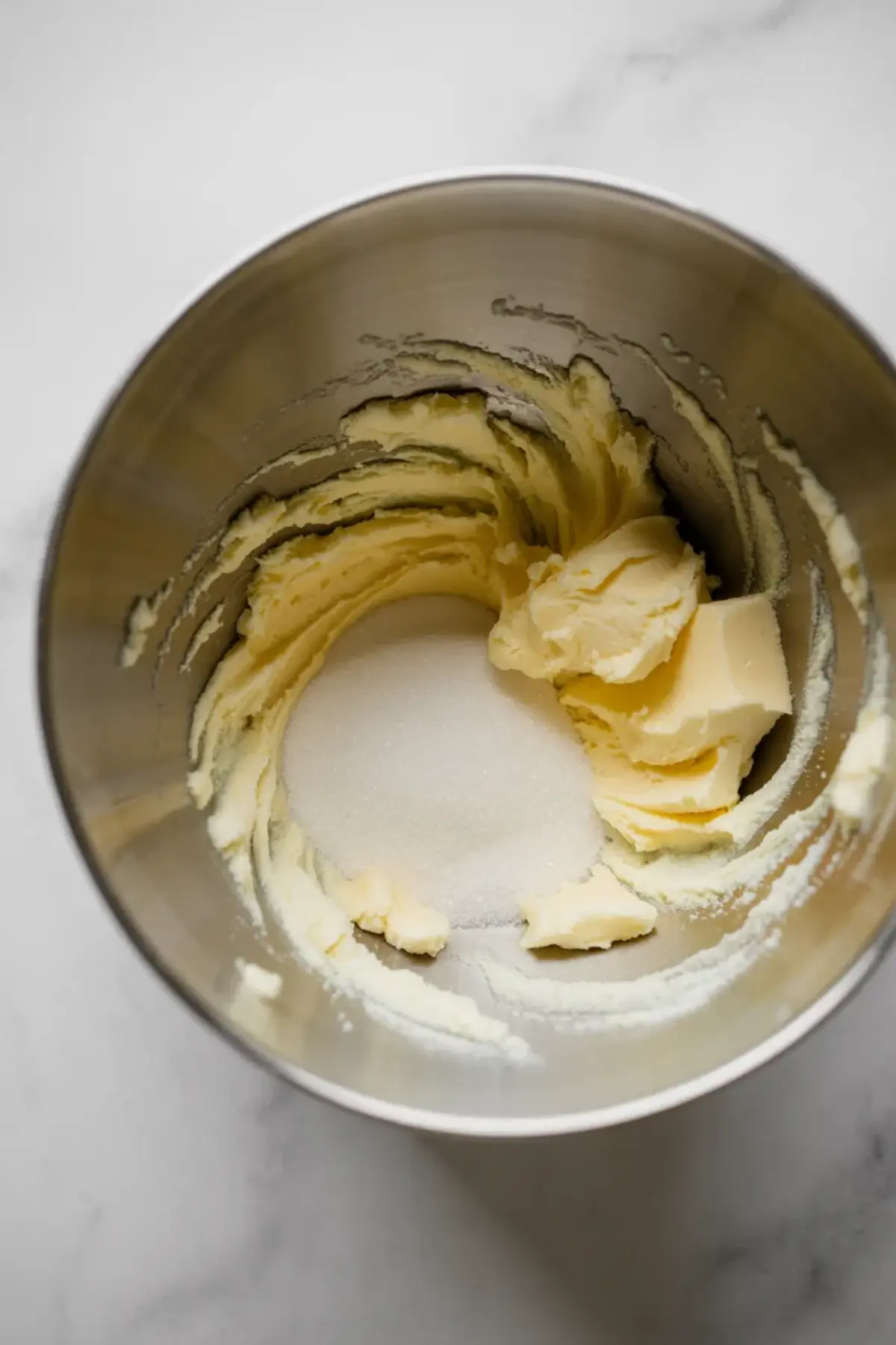 Stand mixer bowl holds softened butter and granulated sugar as the paddle attachment creams the mixture into a light and fluffy base. This image shows the creaming method for gluten free coffee cake batter and homemade cinnamon cake recipe.
