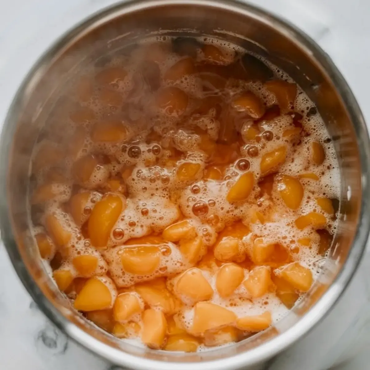 Chopped apricots cook in a pot with bubbles rising as the apricot jam begins to thicken.