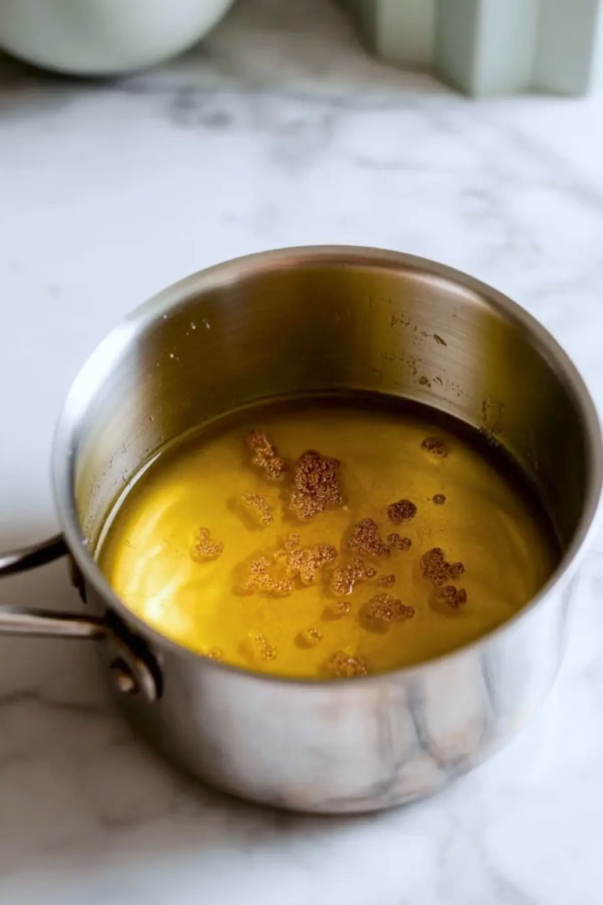 Brown butter in a small saucepan with toasted milk solids for the crumble topping on blueberry cheesecake crumb bars.