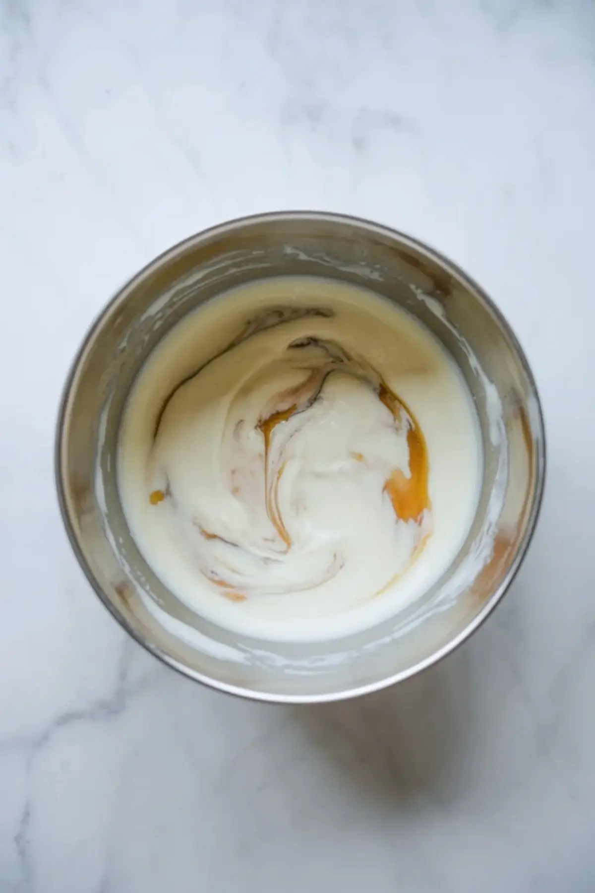 Yogurt and honey mixture swirled in a bowl for blueberry cheesecake yogurt bark before spreading into the pan.
