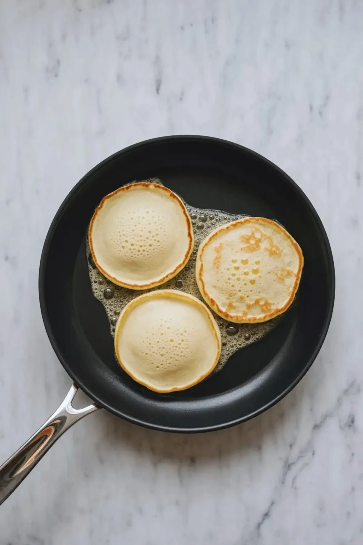 A finished stack of coconut cream pancakes sits on a plate with creamy topping and syrup for a sweet tropical breakfast.